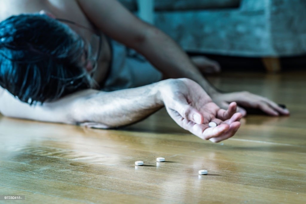 Mature man lying on the floor at home for overdose after pills.