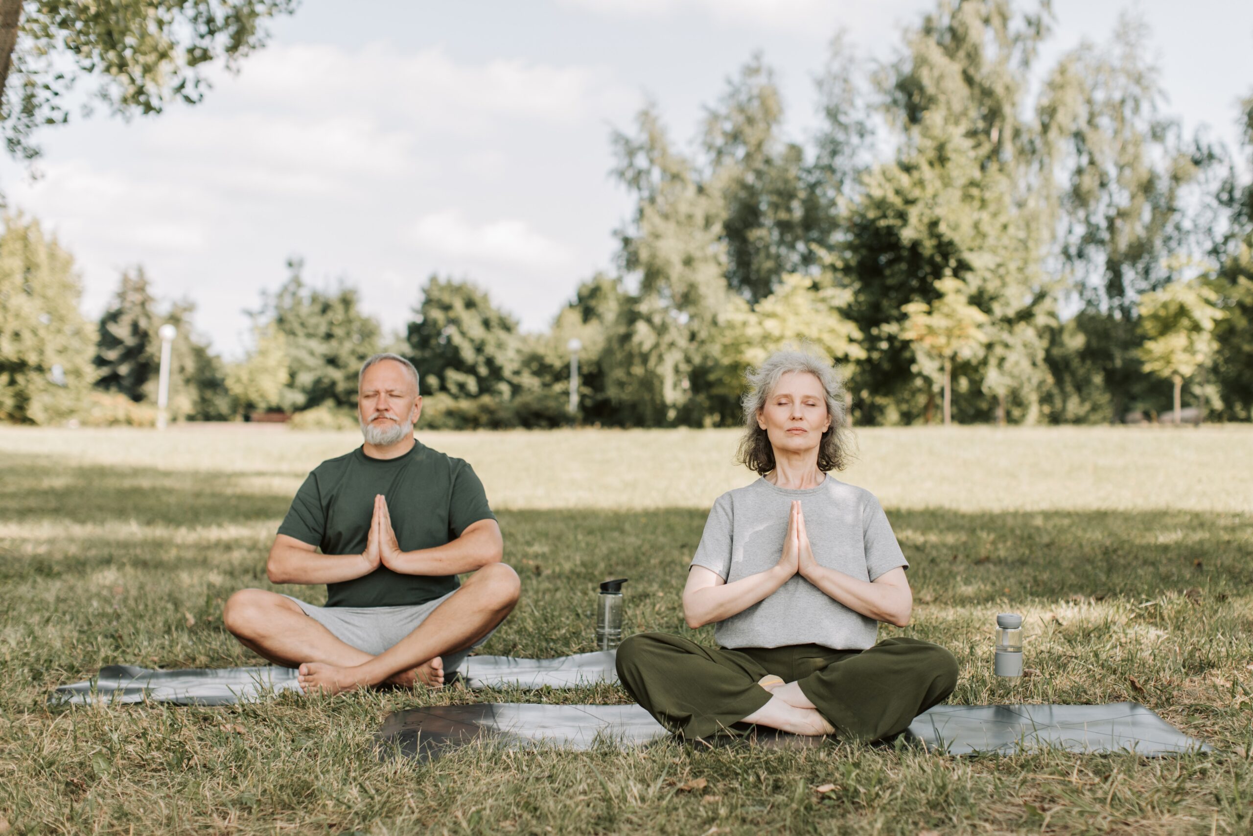 A man and woman meditating in an open field
