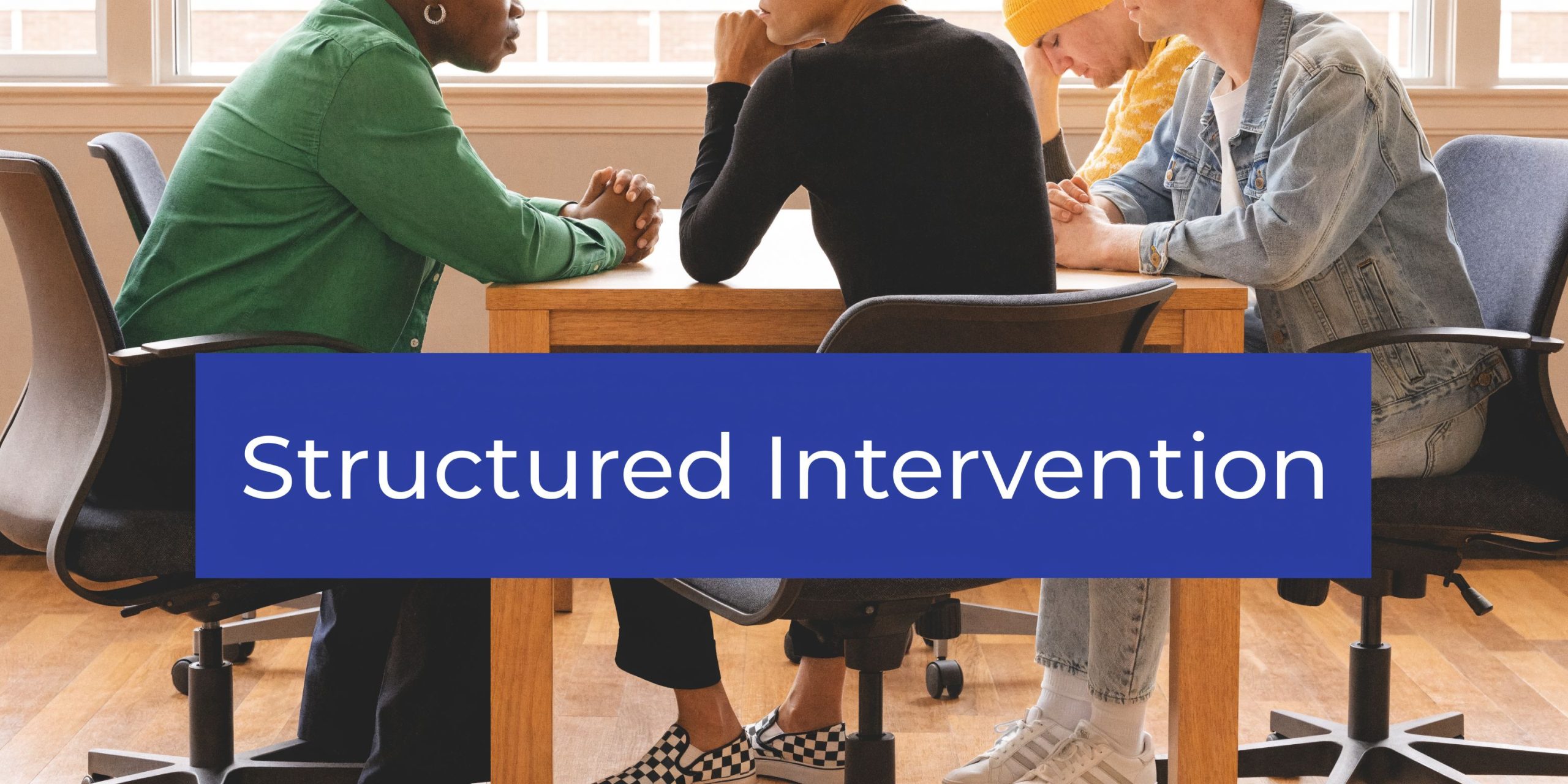 A group of friends sitting around a table having a serious conversation about intervention.