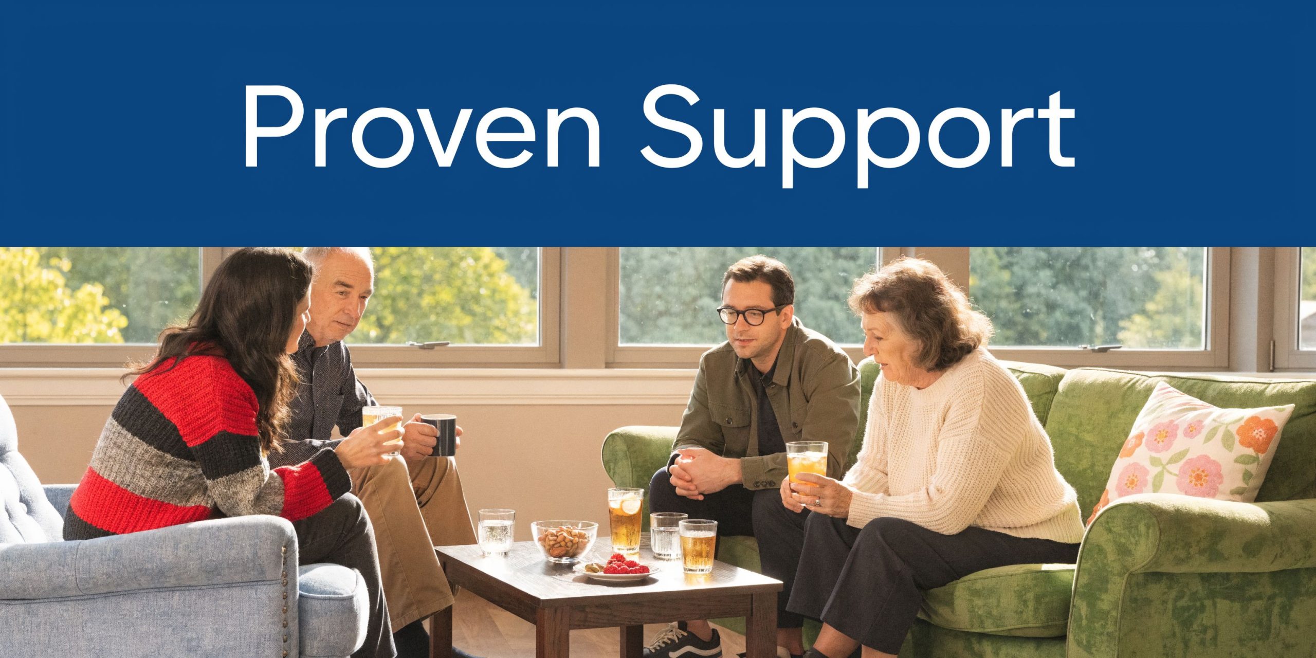 Four adults sitting on sofas in a comfortable living room, drinking and talking during a support meeting.