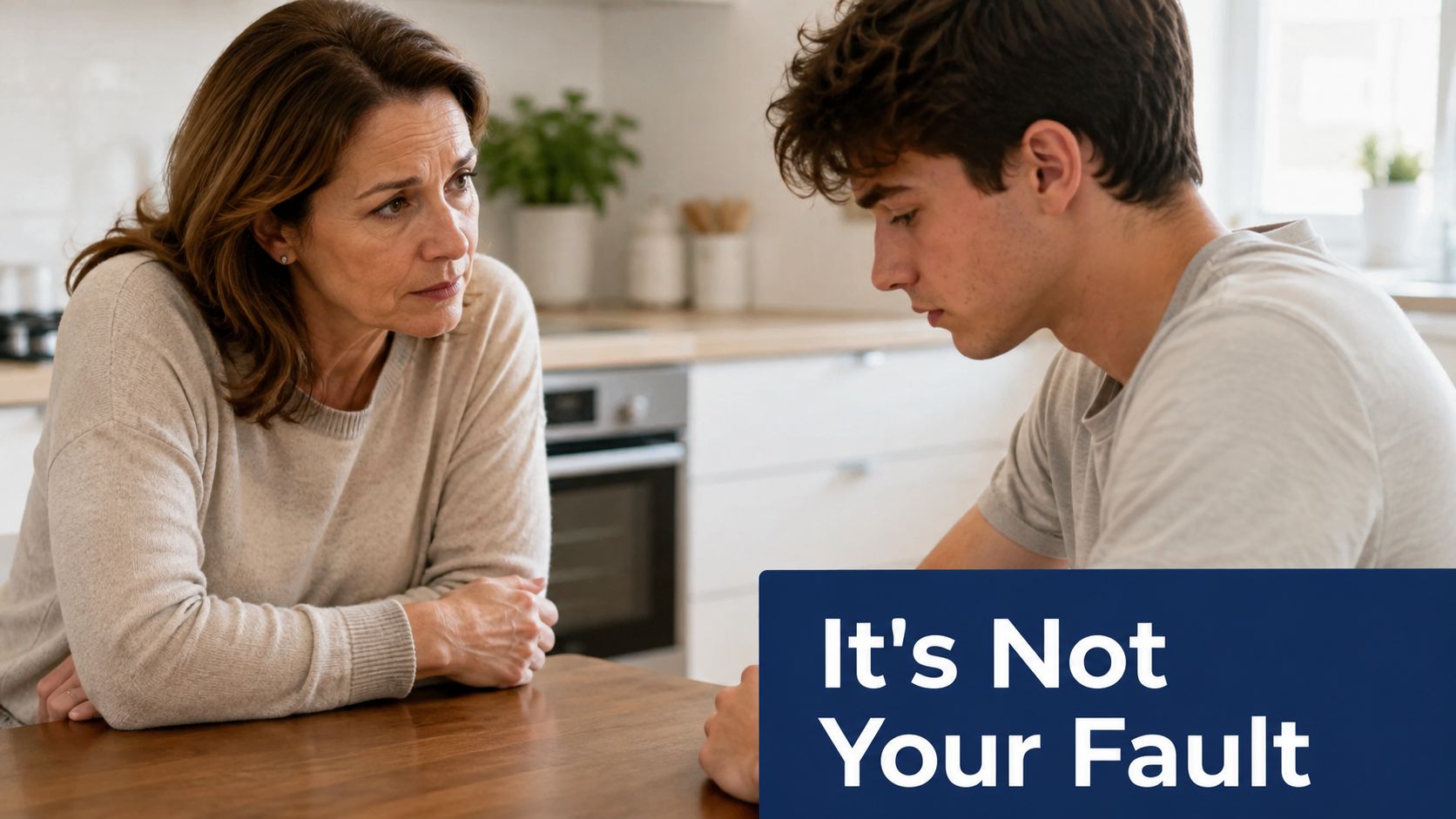 A caring mother supporting her sad son during a serious conversation at a kitchen table.